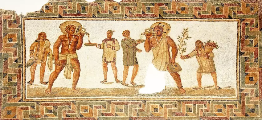 From the 2nd century AD in Dougga, Tunisia, a Roman mosaic depicts two slaves bearing wine jars, adorned in standard slave attire and necklaces featuring amulets to ward off the evil eye. To the left, a young slave carries water and towels, while the one on the right holds a branch and a basket filled with flowers.